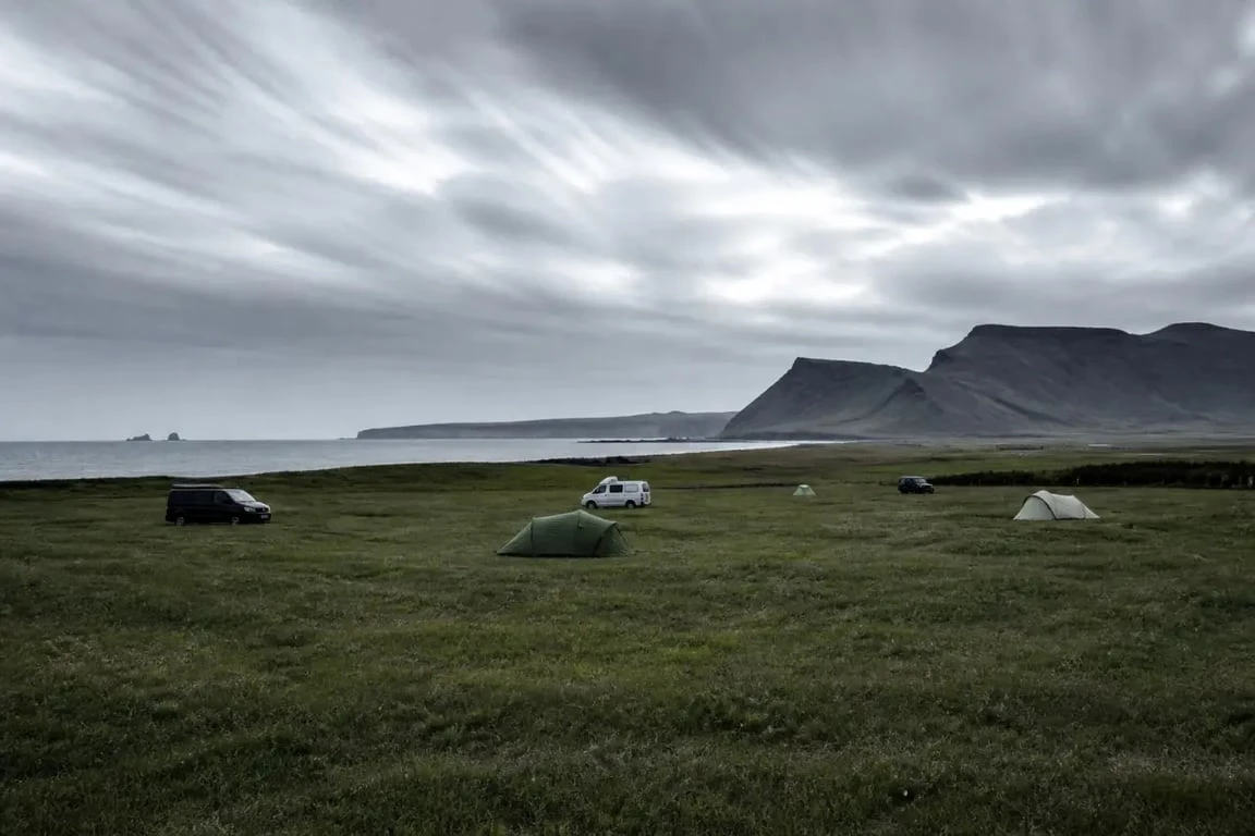 Camping vik islande au pied des paysages volcaniques de Vík, avec tentes et vans sur terrain herbeux