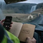 Movies on road trip : téléphone audio et carnet sur un road trip en voiture, vue sur route islandaise