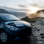 Road trip Islande été : voiture devant une cascade, vapeur et fjord
