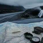 Planifier un road trip en Islande : carte froissée sur un 4x4, route humide et lave noire